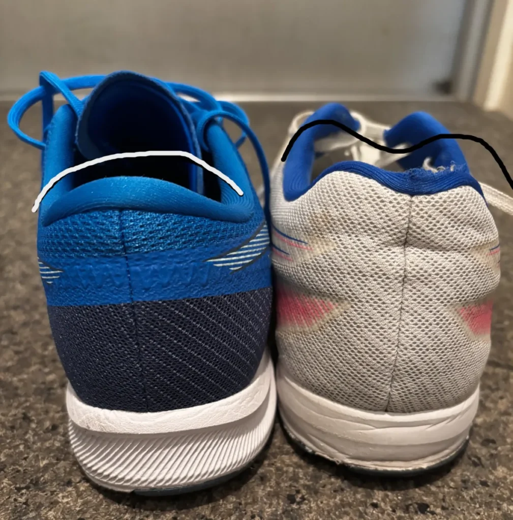 2足のアシックスランニングシューズを後方から撮影。左は青と濃い青色の新しいシューズ、右は白とピンクのラインが入った使い込まれたシューズ。白い線と黒い線で、それぞれの履き口の高さの違いが強調されている。