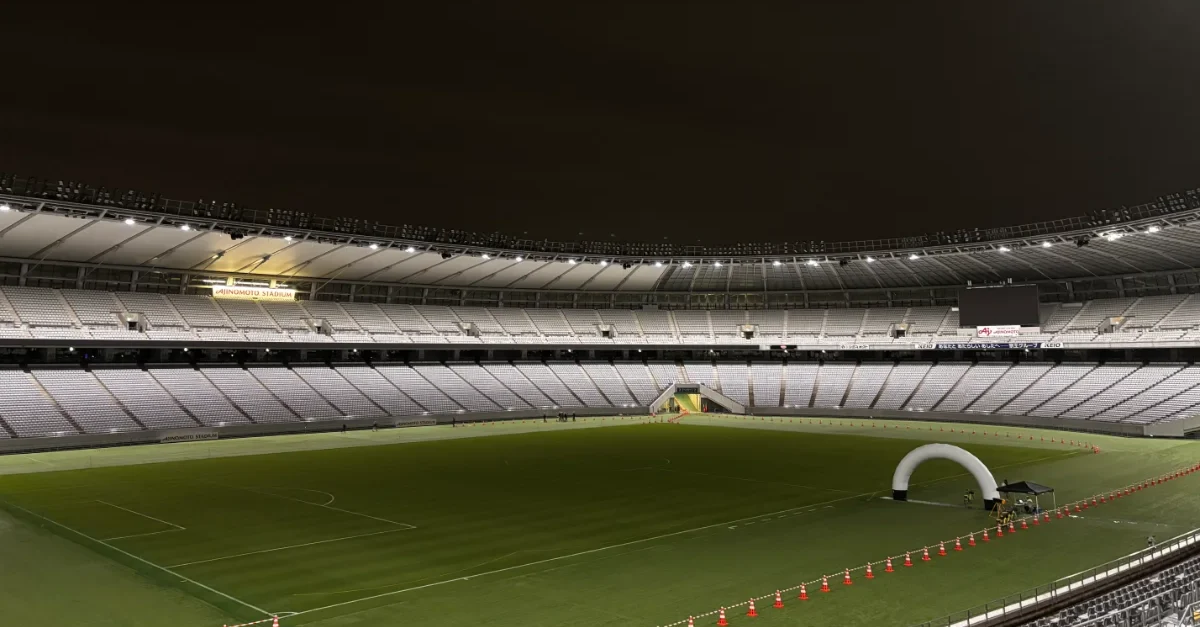 夜間に照明で照らされたスタジアムの広大な天然芝グラウンドと無人の観客席